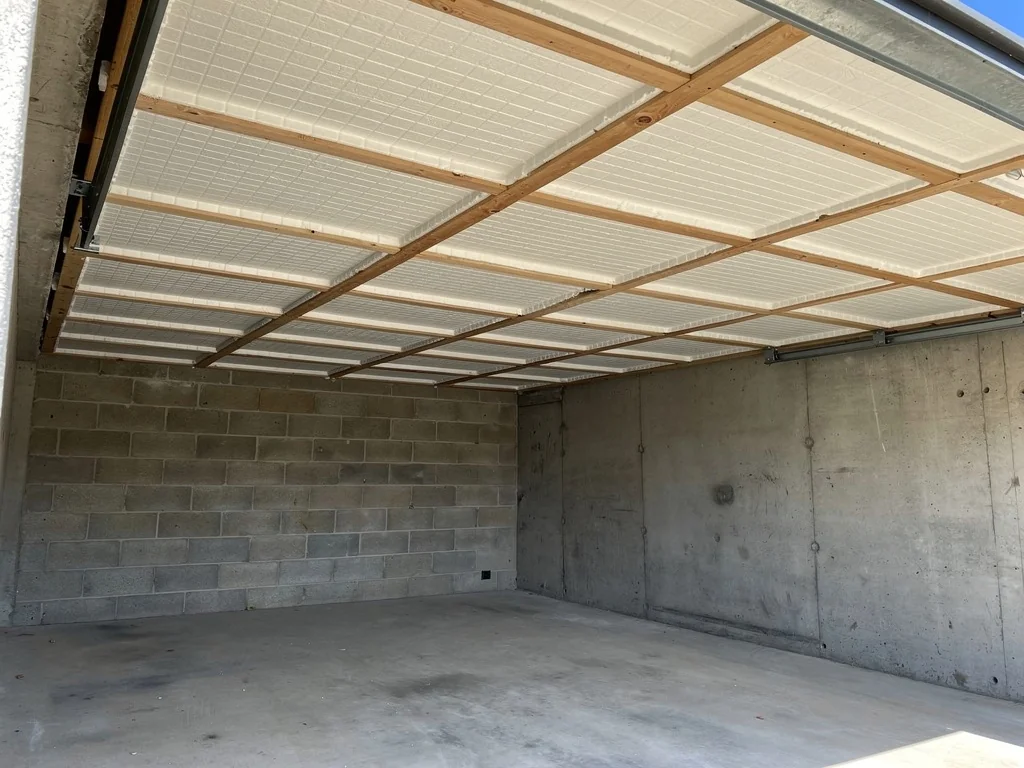 Panneaux isolants fixés au plafond d'un garage sous le plancher